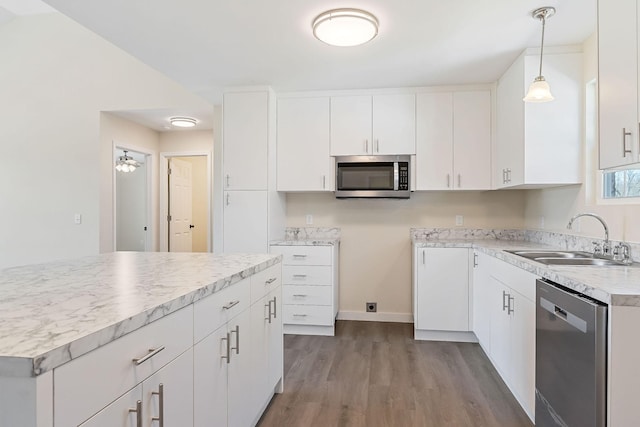 kitchen with dark wood-type flooring, decorative light fixtures, white cabinets, stainless steel appliances, and a sink