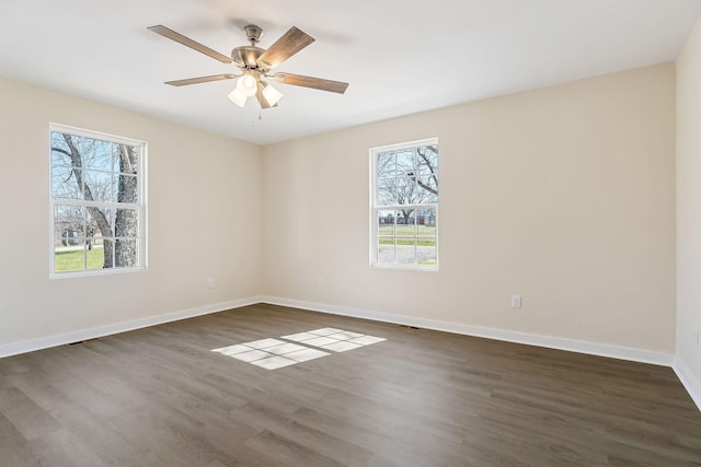 empty room with baseboards, a ceiling fan, and dark wood-style flooring