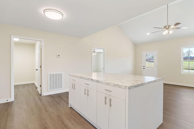 kitchen featuring vaulted ceiling, a ceiling fan, visible vents, and a center island