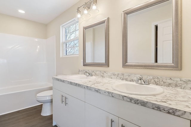 bathroom featuring double vanity, toilet, wood finished floors, and a sink