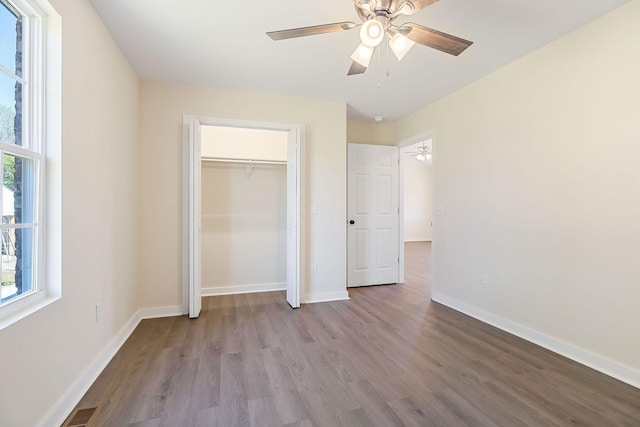 unfurnished bedroom featuring visible vents, baseboards, a closet, and wood finished floors