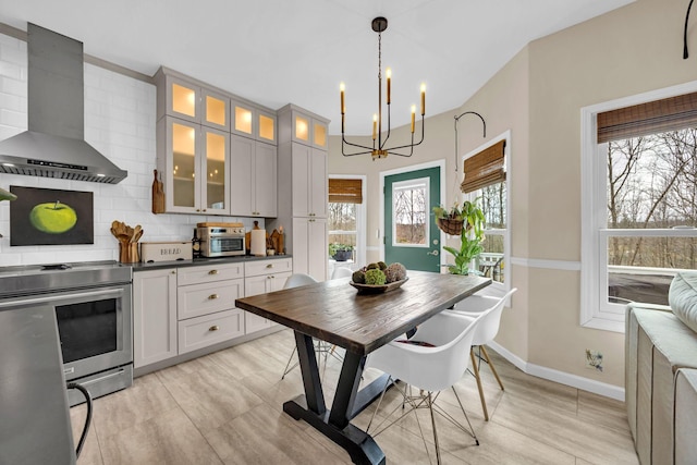 kitchen featuring stainless steel electric range oven, tasteful backsplash, dark countertops, glass insert cabinets, and wall chimney range hood