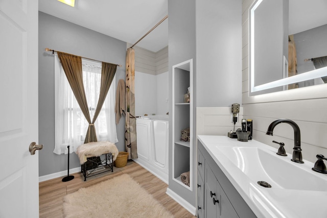 full bath featuring curtained shower, vanity, baseboards, and wood finished floors