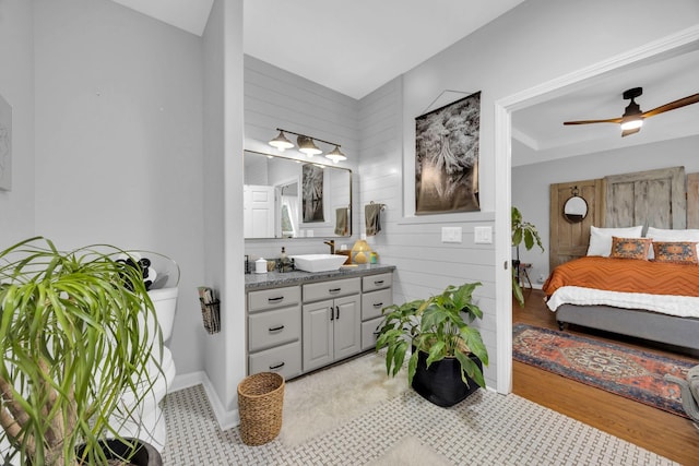 bathroom with a ceiling fan, wood walls, vanity, and baseboards