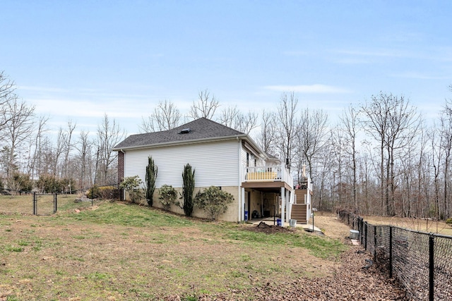 view of property exterior with a wooden deck, roof with shingles, stairs, fence, and a yard