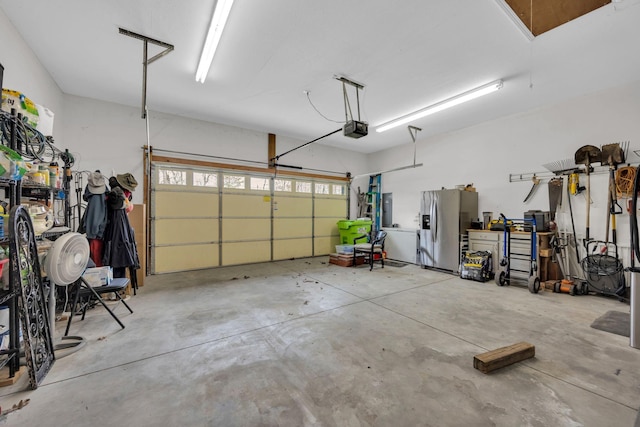 garage with a garage door opener and stainless steel fridge