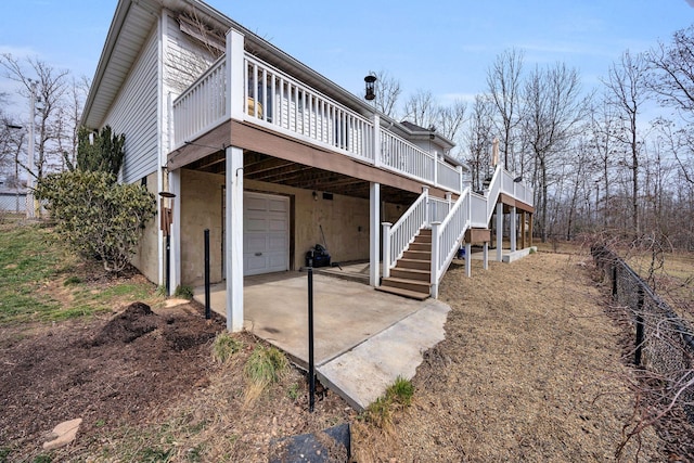 view of side of home featuring stairs, driveway, an attached garage, and a wooden deck