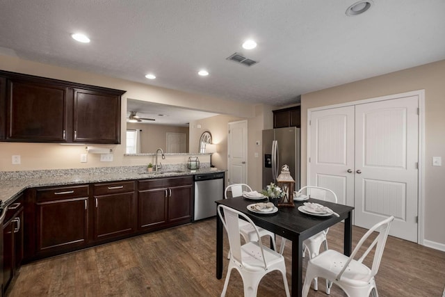 kitchen with dark brown cabinetry, a sink, visible vents, appliances with stainless steel finishes, and dark wood-style floors