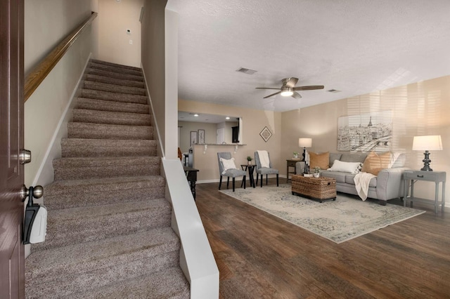 stairs with visible vents, a ceiling fan, a textured ceiling, wood finished floors, and baseboards