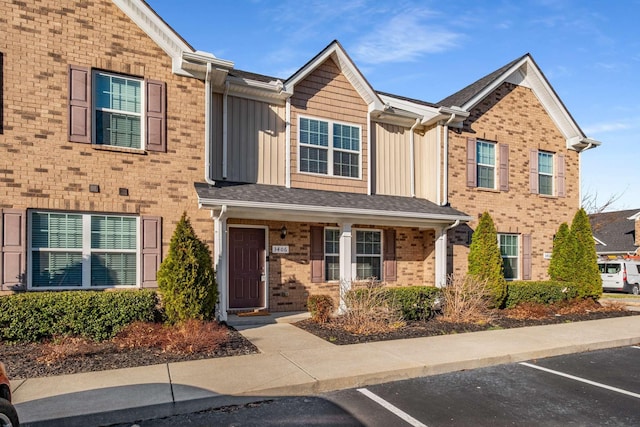 townhome / multi-family property featuring uncovered parking, board and batten siding, and brick siding