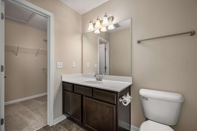 bathroom with visible vents, a spacious closet, toilet, vanity, and baseboards