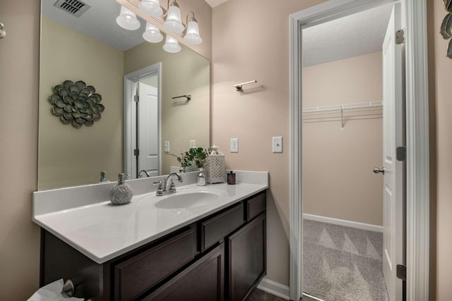 bathroom with baseboards, visible vents, a chandelier, and vanity