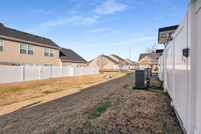 view of yard featuring a residential view, fence, and central air condition unit