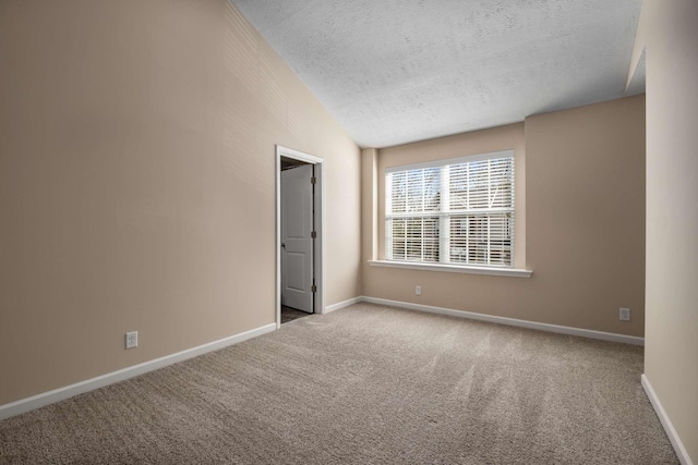 carpeted empty room featuring lofted ceiling, a textured ceiling, and baseboards