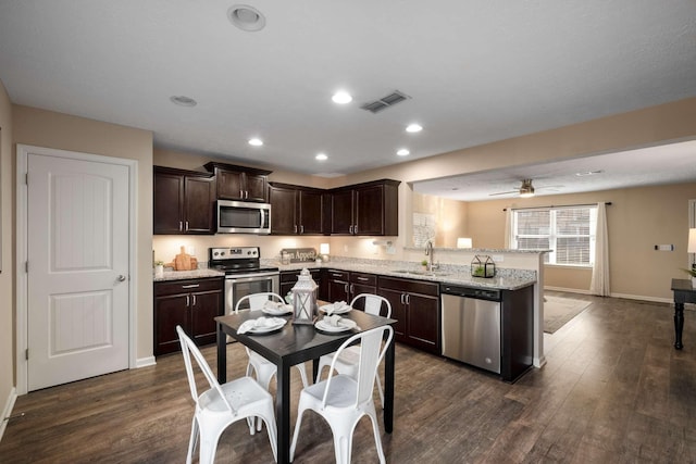 kitchen featuring dark brown cabinetry, stainless steel appliances, a peninsula, dark wood-style flooring, and visible vents