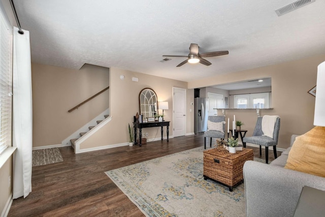 living room featuring stairway, wood finished floors, visible vents, and baseboards