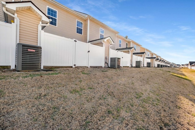 rear view of house with central AC unit and fence