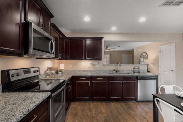 kitchen with dark wood-style floors, stainless steel appliances, visible vents, a sink, and dark brown cabinetry