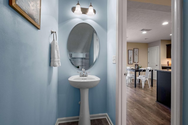 bathroom featuring a textured ceiling, recessed lighting, wood finished floors, visible vents, and baseboards