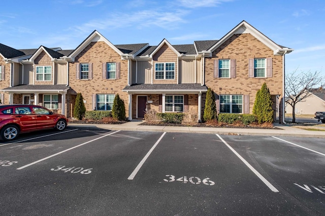 townhome / multi-family property featuring uncovered parking and brick siding