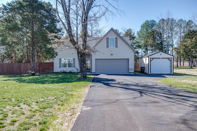 traditional home featuring a front lawn, fence, a garage, and an outdoor structure