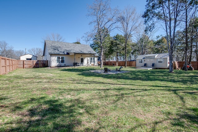 view of yard with a patio area, an outbuilding, a fenced backyard, and a fire pit