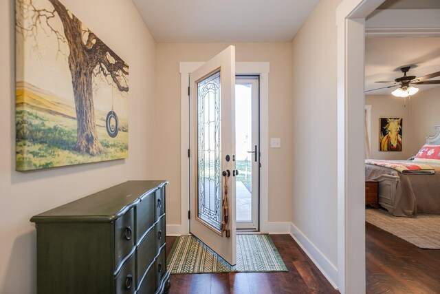 foyer entrance with dark wood finished floors, baseboards, and ceiling fan