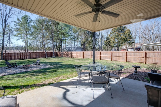 view of patio / terrace featuring a fenced backyard, outdoor dining area, ceiling fan, and an outdoor fire pit