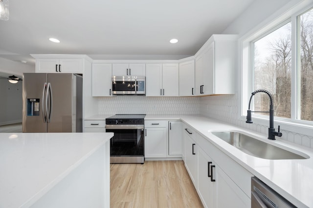 kitchen with white cabinets, plenty of natural light, stainless steel appliances, and a sink