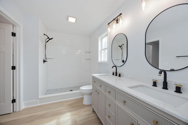 bathroom with double vanity, tiled shower, and a sink