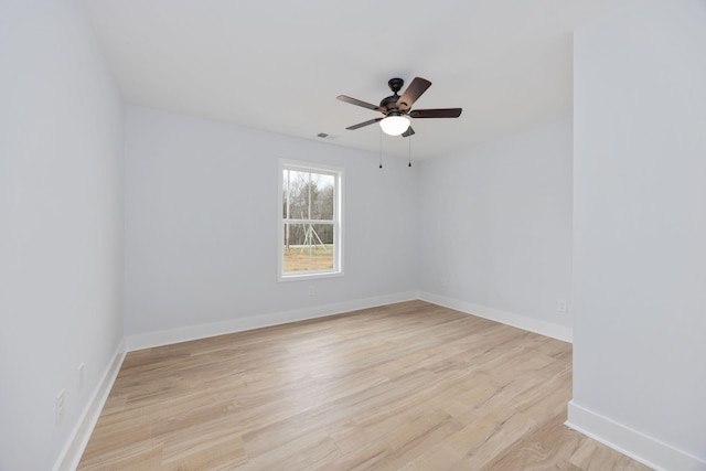 spare room featuring visible vents, light wood-type flooring, a ceiling fan, and baseboards