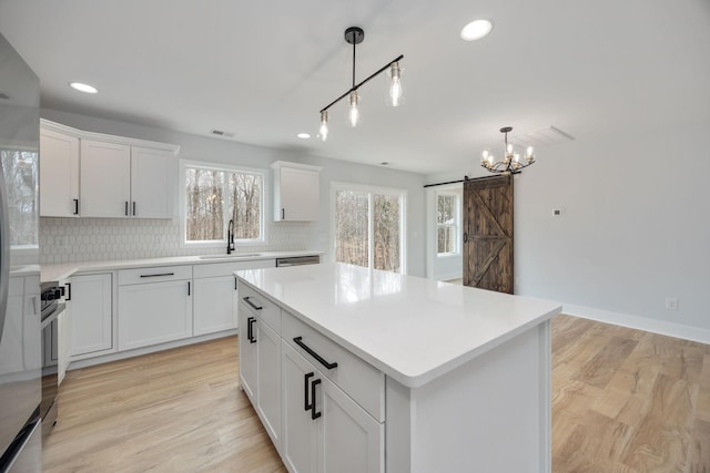 kitchen featuring tasteful backsplash, a sink, light wood finished floors, and a barn door