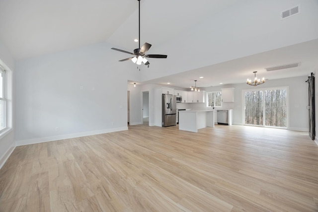 unfurnished living room featuring lofted ceiling, ceiling fan with notable chandelier, visible vents, baseboards, and light wood finished floors