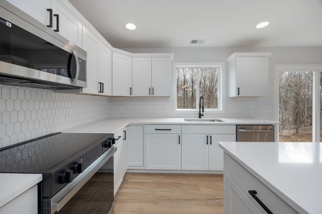 kitchen featuring appliances with stainless steel finishes, light countertops, visible vents, and a sink