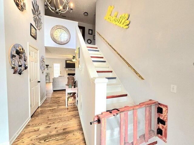 staircase featuring an inviting chandelier and wood finished floors