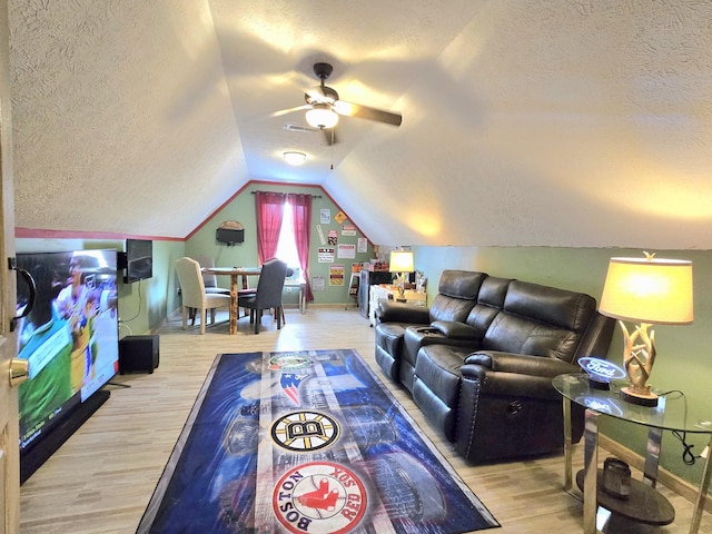 interior space with lofted ceiling, a ceiling fan, a textured ceiling, wood finished floors, and baseboards