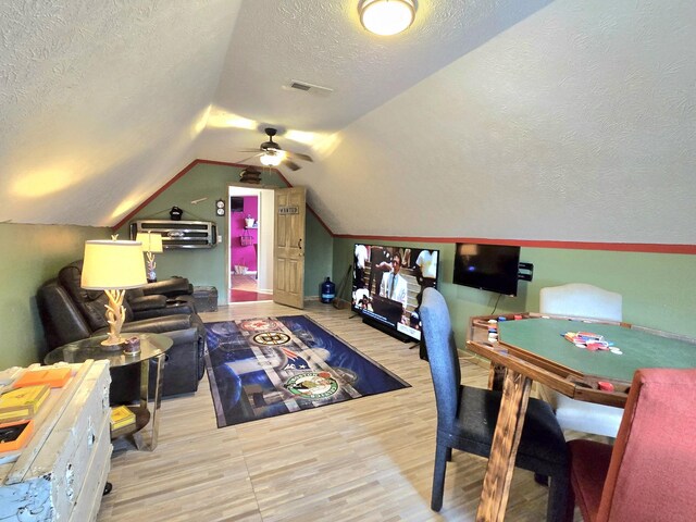 game room featuring vaulted ceiling, a textured ceiling, wood finished floors, and visible vents