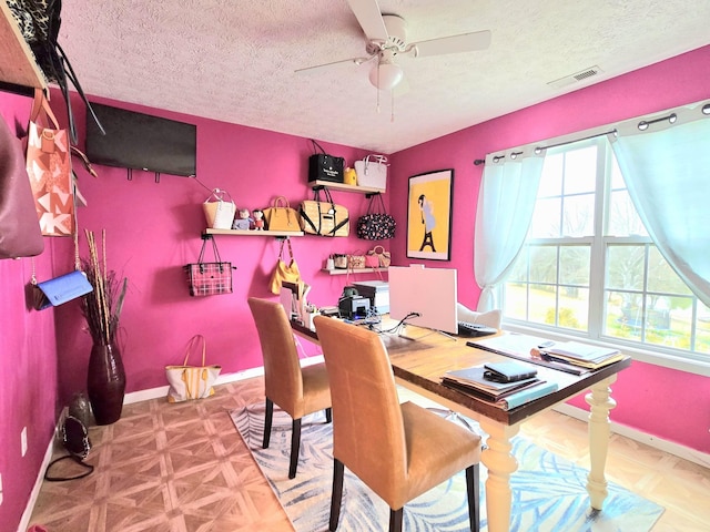 interior space with baseboards, visible vents, ceiling fan, and a textured ceiling