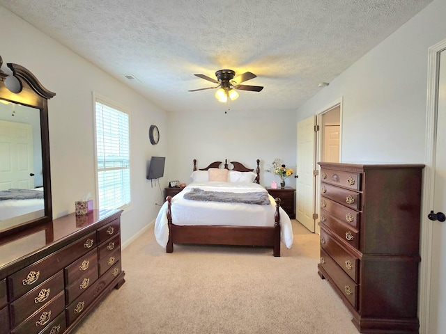 bedroom featuring ceiling fan, a textured ceiling, visible vents, and light colored carpet