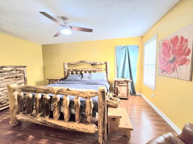 bedroom featuring ceiling fan, baseboards, and wood finished floors