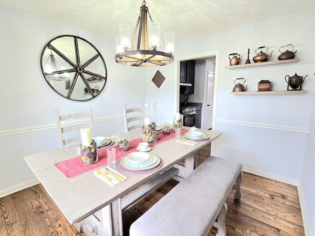 dining room featuring baseboards, a textured ceiling, an inviting chandelier, and wood finished floors