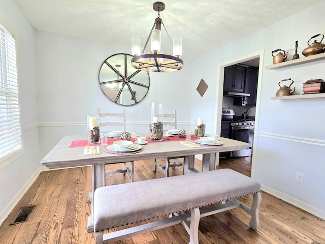 dining room featuring a healthy amount of sunlight, a notable chandelier, visible vents, and wood finished floors