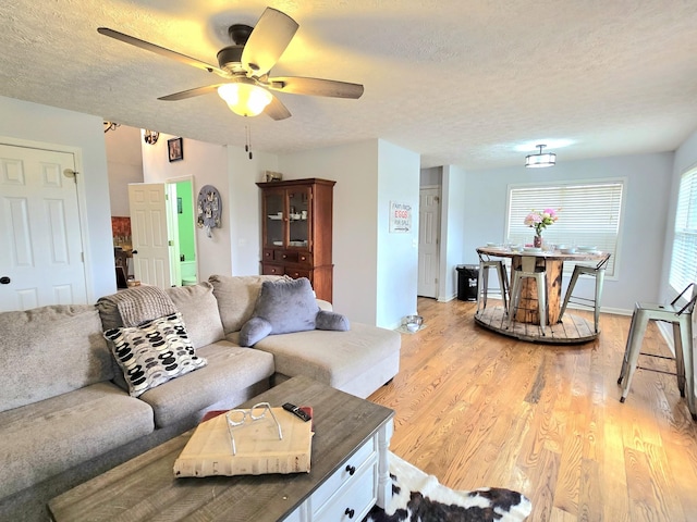 living area featuring a textured ceiling, light wood-style flooring, and a ceiling fan