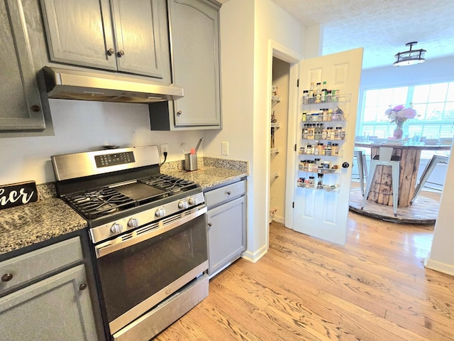 kitchen featuring stainless steel gas range, gray cabinets, and under cabinet range hood