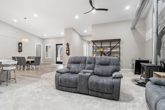 living room featuring a wood stove, ceiling fan, baseboards, and recessed lighting