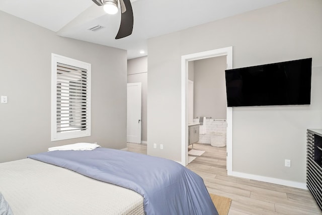 bedroom featuring ensuite bathroom, a ceiling fan, baseboards, visible vents, and light wood-style floors