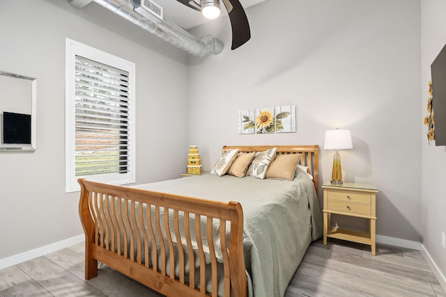 bedroom featuring a ceiling fan, wood finished floors, visible vents, and baseboards