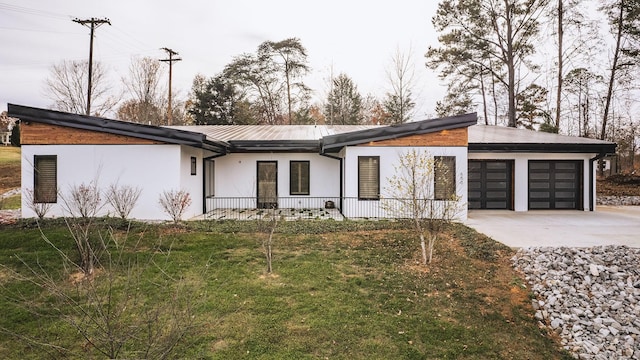 view of front of house with concrete driveway, a front lawn, an attached garage, and stucco siding