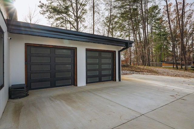 garage featuring driveway and fence