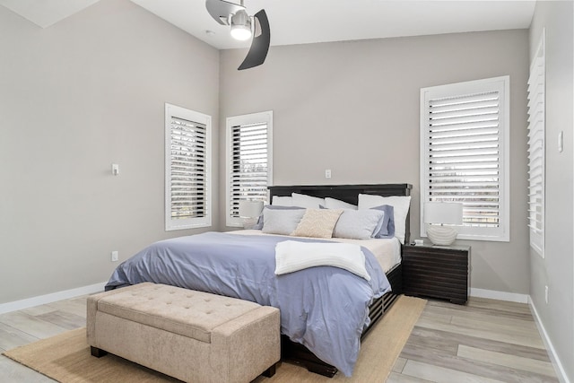 bedroom with light wood finished floors, baseboards, and a ceiling fan